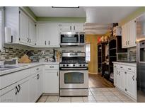 Well-lit kitchen features white cabinets, stainless steel appliances, and stone countertops at 3928 Edgemoor Way, Las Vegas, NV 89121