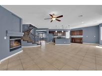 Bright, open-concept living room with a fireplace, tile floors, and a staircase leading to the upper level at 4063 Lower Saxon Ave, North Las Vegas, NV 89085