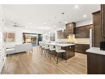A spacious kitchen with a large island, modern appliances, and stylish pendant lighting overlooking a living room at 52 Reverie Heights Ave, Henderson, NV 89011