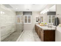 Bright bathroom featuring double sinks, granite countertops, a large mirror, and a spacious walk-in shower at 711 Florence Isle Ave, Henderson, NV 89015