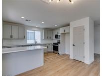 Bright, open kitchen featuring stainless steel appliances, light gray cabinets, and a spacious island with light wood floors at 9855 Ashton Pines Ct, Las Vegas, NV 89147
