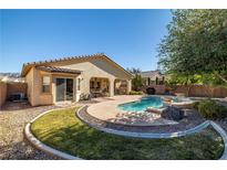 Inviting backyard pool with landscaped rock feature and covered patio, perfect for outdoor relaxation and entertaining at 4937 Semifonte Dr, Pahrump, NV 89061