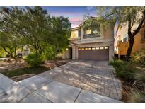 Two-story home with neutral paint, balcony, brick driveway and mature trees at dusk at 5080 Plymouth Bay Ct, Las Vegas, NV 89141