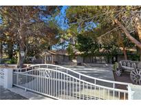 Charming single-story home with a decorative white fence, mature trees, and stone accents at 5159 N Monte Cristo Way, Las Vegas, NV 89149