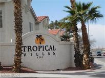 Community sign for Tropical Villas with palm trees and tropical landscaping at the entrance at 6201 E Lake Mead Blvd # 218, Las Vegas, NV 89156
