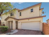 Tan two-story home with a two-car garage, brick driveway, and manicured landscaping at 914 Appaloosa Hills Ave, North Las Vegas, NV 89081