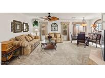 Inviting living room featuring plush sofas, a ceiling fan, and elegant decor with an adjacent dining area at 9522 Arrowhead Falls Ct, Las Vegas, NV 89148