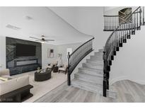 Bright living room showcasing a marble fireplace, sleek ceiling fan, and a stylish staircase with black railing at 9541 Summersweet Ct, Las Vegas, NV 89123