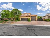 Attractive two-story home featuring a tile roof, two-car garage, and brick-paved driveway, with mature landscaping at 9749 Glistening Brook Ct, Las Vegas, NV 89149