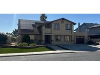 Two-story home featuring solar panels, a two-car garage, green front yard, and a tan exterior at 4356 Sabadell St, Las Vegas, NV 89121