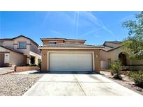 Beige home featuring a large, two-car garage and a concrete driveway with desert landscaping under a bright blue sky at 6287 Stone Hollow Ave, Las Vegas, NV 89156