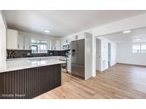 Modern kitchen features stainless steel appliances, white cabinetry, quartz countertops, and a stylish backsplash and wood flooring at 6308 Lawton Ave, Las Vegas, NV 89107