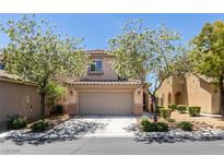 Inviting two-story home with a two-car garage and mature flowering trees in a well-maintained front yard at 8733 Autumn Teal Ave, Las Vegas, NV 89178