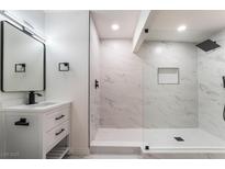 Modern bathroom featuring marble tile, glass shower, white vanity with black fixtures, and a contemporary mirror at 934 Lewis Ct, Henderson, NV 89015