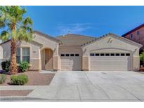 Beige single story home with a three car garage, landscaped yard, and palm tree under a clear, blue sky at 981 Buffalo River Ave, Henderson, NV 89002
