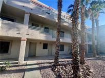 Beige stucco condo complex with palm trees, pedestrian walkways and exterior stairs at 2064 Mesquite Ln # 102, Laughlin, NV 89029