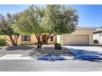 Charming single-story home featuring a desert landscape, mature trees, and an attached two-car garage at 2183 Waterton Rivers Dr, Henderson, NV 89044