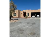 Beige house with desert landscaping and a two-car garage beneath the main structure at 3551 Sagebrush Ave, Pahrump, NV 89048