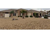 Single-story home with low maintenance landscaping featuring rock ground cover and desert shrubs and palm trees at 5450 Grain Mill Rd, Pahrump, NV 89061