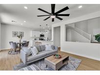 Bright, open-concept living space with modern furnishings flowing into a well-appointed kitchen and staircase at 6282 Dollar Bill Ct, Las Vegas, NV 89141