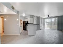 Bright open-concept living room with gray tiling, fireplace, modern kitchen, and sliding glass door to the balcony at 7189 S Durango Dr # 208, Las Vegas, NV 89113