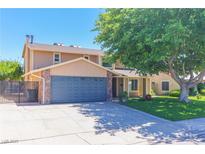 Charming two-story home with a well-manicured lawn, mature tree and a driveway leading to a spacious two car garage at 1440 Rawhide Rd, Boulder City, NV 89005