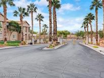 Welcoming community entrance with gated access and lush landscaping featuring mature palm trees under a bright sky at 2110 Los Feliz St # 1066, Las Vegas, NV 89156