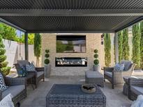 Inviting covered patio boasts comfortable seating, an outdoor fireplace, and a mounted TV, perfect for outdoor enjoyment at 2400 Trissino Ct, Henderson, NV 89044