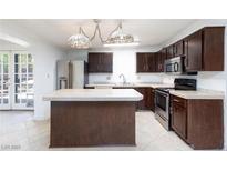A cozy kitchen showcasing dark wood cabinets, a stainless steel refrigerator, and a functional center island at 2825 Burnham Ave, Las Vegas, NV 89169