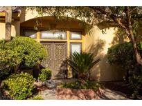 Inviting home entrance with ornate double doors, lush landscaping, and warm, welcoming ambiance at 4554 Blue Mesa Way, Las Vegas, NV 89129
