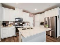 Beautiful kitchen features white cabinetry, stainless steel appliances, an island, and brick-style backsplash at 6228 Haiku Stairs St, Las Vegas, NV 89148