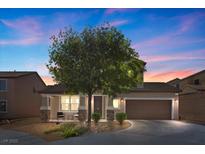 Charming two-story home with a well-manicured front yard and inviting front porch at dusk at 6857 Stone Tower Ct, Las Vegas, NV 89149