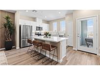 Modern kitchen features an island with bar stool seating, white cabinets, stainless steel appliances and wood-look flooring at 145 Harmonica Ave # Lot 23, Henderson, NV 89015