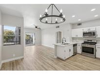 Open-concept living room boasts a modern chandelier, light wood floors, and a stainless steel kitchen at 2201 Ramsgate Dr # 327, Henderson, NV 89074