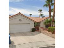 Charming single-story home featuring a terra cotta roof, a two-car garage, and desert landscaping with palm trees at 6581 Monterey Mesa Ct, Las Vegas, NV 89156