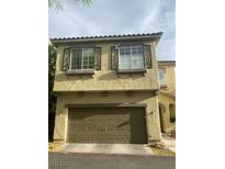 Two story townhouse with a two car garage and decorative window safety bars at 8913 Cambridge Glen Ct, Las Vegas, NV 89149