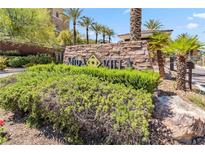 Welcoming stone community sign surrounded by lush landscaping and palm trees under a bright blue sky at 9125 Las Manaitas Ave # 302, Las Vegas, NV 89144