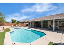 Resort-style backyard featuring a sparkling pool, lounge chairs and covered patio with comfortable seating area at 9362 Wilderness Glen Ave, Las Vegas, NV 89178