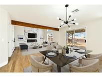 Bright dining area featuring a modern table setting and stylish light fixture and a view into the living room at 1724 Navajo Lake Way, Las Vegas, NV 89128
