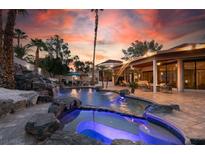 An amazing outdoor area with a custom rock waterfall, gorgeous pool and spa highlighted by a fiery sunset at 2101 Diamond Bar Dr, Las Vegas, NV 89117