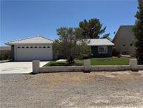Charming single-story home featuring a two-car garage, mature trees, and a well-maintained front yard at 311 Glenoaks St, Pahrump, NV 89048