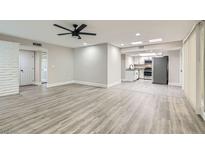 Open living space featuring modern gray wood floors and bright lighting with kitchen area view at 3310 Heritage Pl, Las Vegas, NV 89121