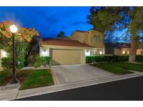 Charming two-story home with a well-maintained lawn, driveway, and two-car garage at dusk at 5125 Turnberry Ln, Las Vegas, NV 89113