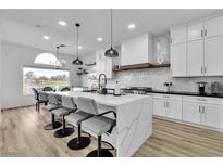 Modern white kitchen featuring an island with waterfall countertop and pendant lighting at 9513 Villa Ridge Dr, Las Vegas, NV 89134