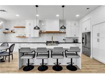 A modern kitchen with white cabinets, an island with bar stools, and stainless steel appliances at 9513 Villa Ridge Dr, Las Vegas, NV 89134