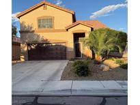 Charming two-story home with a brown two car garage, desert landscaping, and lush palm tree at , North Las Vegas, NV 89031