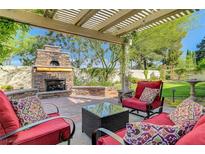 Inviting outdoor patio with stone fireplace, pergola, and comfortable seating, perfect for entertaining at 1432 Castle Crest Dr, Las Vegas, NV 89117