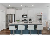 Modern kitchen with white cabinets, stainless steel appliances, and a large center island with seating at 3729 Canis Minor Ln # 10206, Henderson, NV 89052
