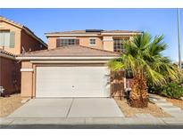 Two-story home featuring a two car garage, desert landscaping, and a palm tree at 5456 Raccoon Valley Ln, Las Vegas, NV 89122