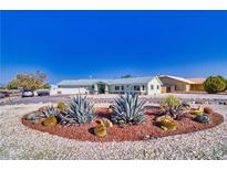 Desert landscaping and white gravel surround this single-story home with a matching detached garage at 6490 Wagon Wheel Ct, Pahrump, NV 89061